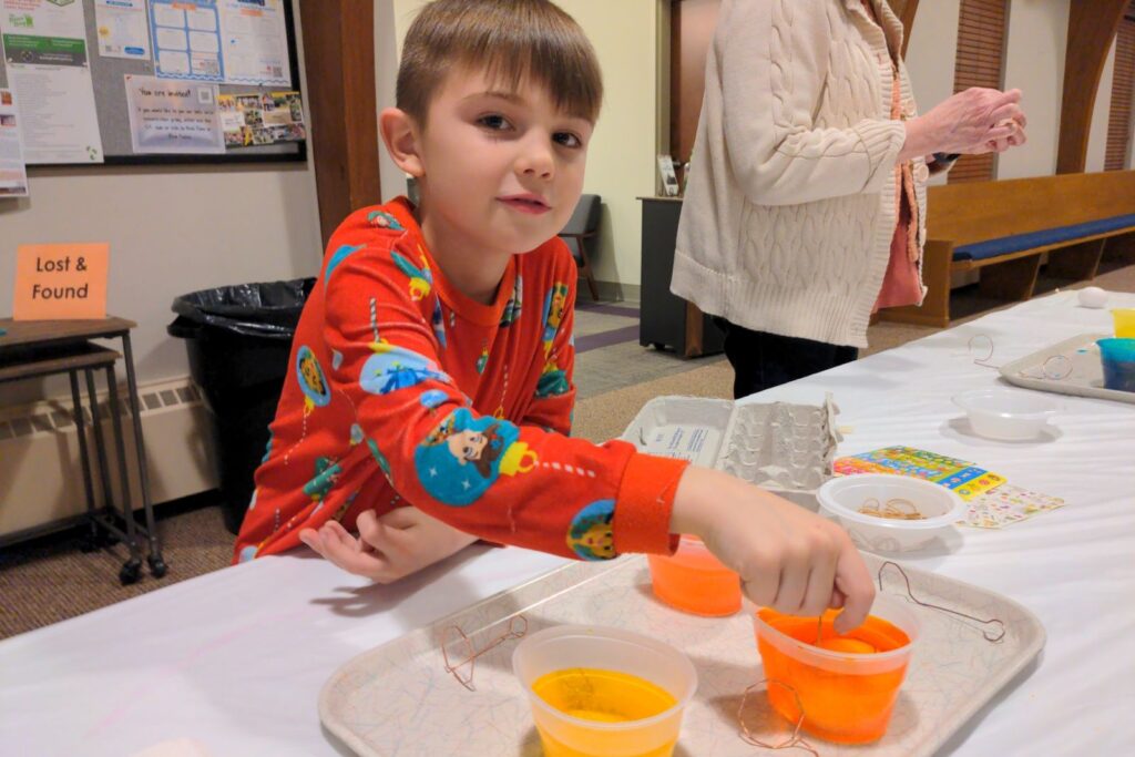 A boy dyeing Easter eggs at Kids Club