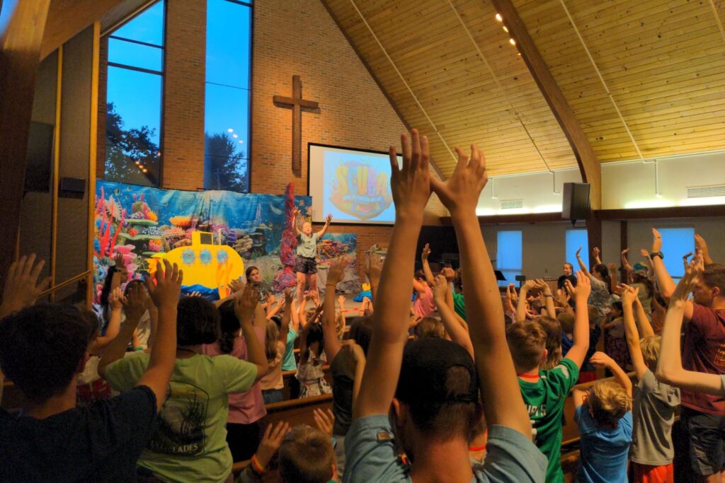 A sanctuary full of kids with hands in the air during VBS worship